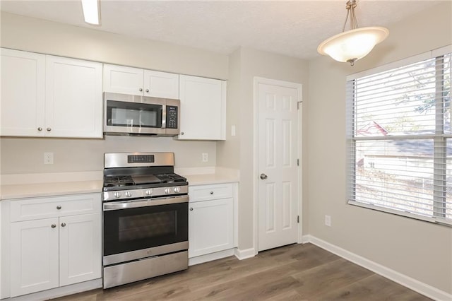 kitchen with white cabinetry, pendant lighting, dark hardwood / wood-style floors, and appliances with stainless steel finishes