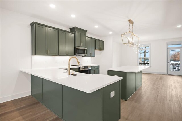 kitchen with kitchen peninsula, hanging light fixtures, dark hardwood / wood-style floors, and appliances with stainless steel finishes