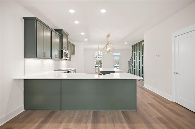 kitchen with kitchen peninsula, stove, pendant lighting, wood-type flooring, and a notable chandelier