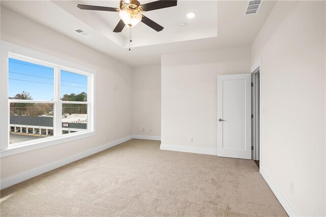 carpeted empty room featuring a raised ceiling and ceiling fan