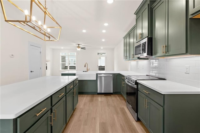 kitchen with ceiling fan, green cabinets, light wood-type flooring, and stainless steel appliances