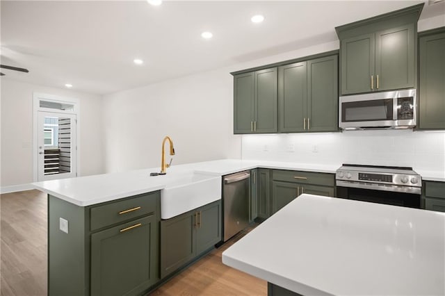 kitchen featuring green cabinets, sink, stainless steel appliances, and light hardwood / wood-style flooring