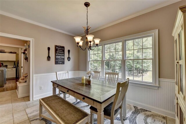 tiled dining room featuring crown molding, a chandelier, and a wealth of natural light