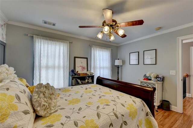 bedroom with ceiling fan, crown molding, and light hardwood / wood-style floors