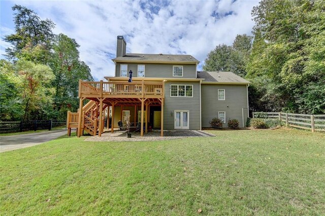 rear view of property featuring a patio area, a deck, and a yard