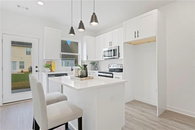 170 Chandler Trce, Covington, GA 30016 - kitchen with stainless steel appliances, white cabinetry, a center island, a kitchen breakfast bar, and pendant lighting
