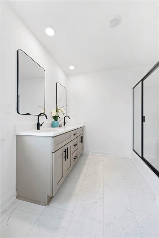 170 Chandler Trce, Covington, GA 30016 - bathroom featuring marble finish flooring, double vanity, recessed lighting, baseboards, and a shower with door
