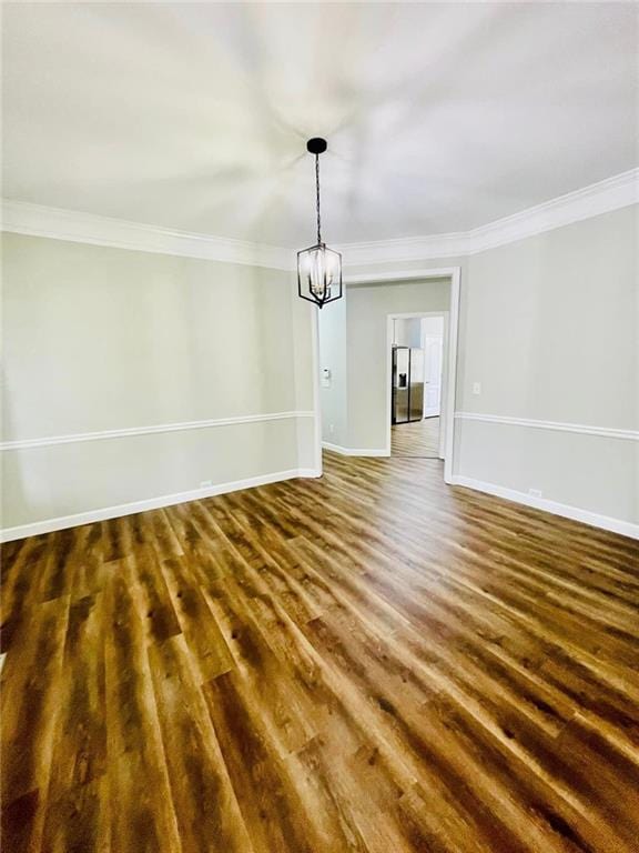 unfurnished dining area with crown molding, dark wood-style flooring, a notable chandelier, and baseboards