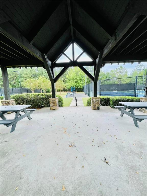 view of property's community featuring a tennis court, fence, a gazebo, and a patio