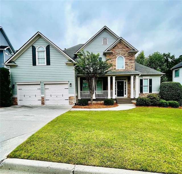 traditional-style home featuring a porch, an attached garage, stone siding, driveway, and a front lawn