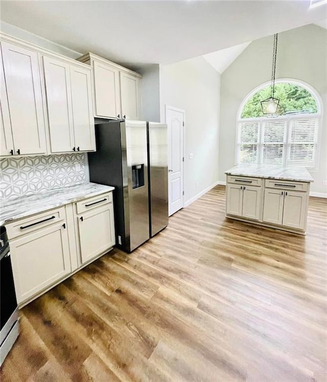 kitchen with tasteful backsplash, white cabinets, vaulted ceiling, stainless steel appliances, and light wood-type flooring