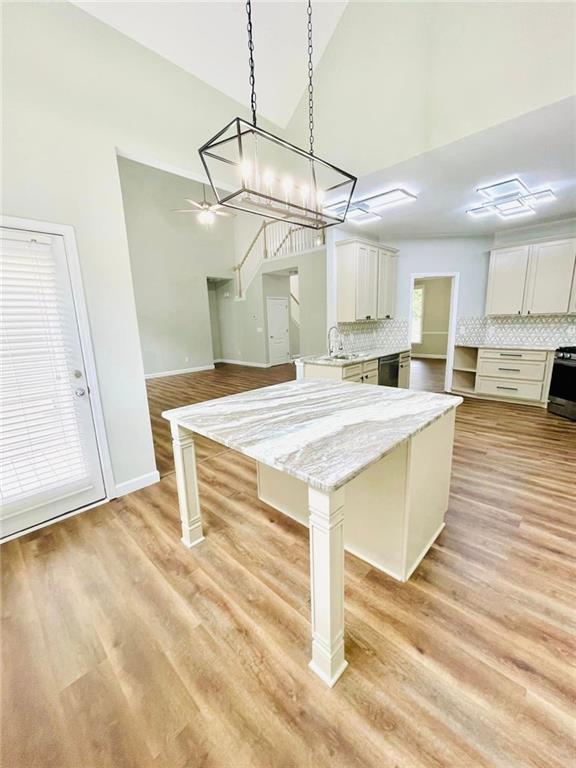 kitchen with a kitchen island, white cabinetry, hanging light fixtures, and a kitchen bar