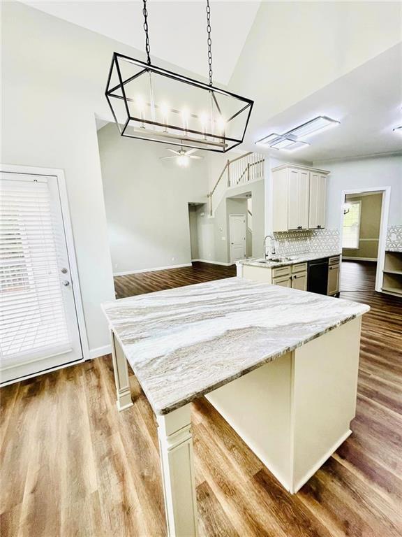 kitchen with decorative light fixtures, light wood-style floors, white cabinets, a sink, and a peninsula