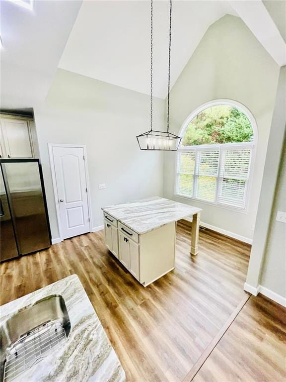 dining room featuring high vaulted ceiling, light wood-style floors, and baseboards