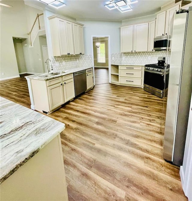 kitchen with stainless steel appliances, light stone countertops, light wood-style flooring, and open shelves