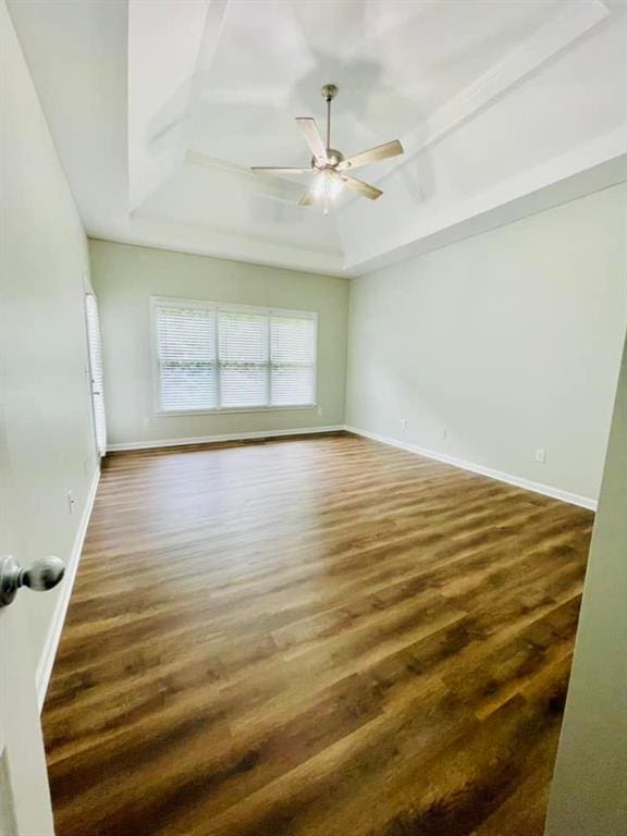 unfurnished room featuring baseboards, a tray ceiling, ceiling fan, and dark wood-style flooring