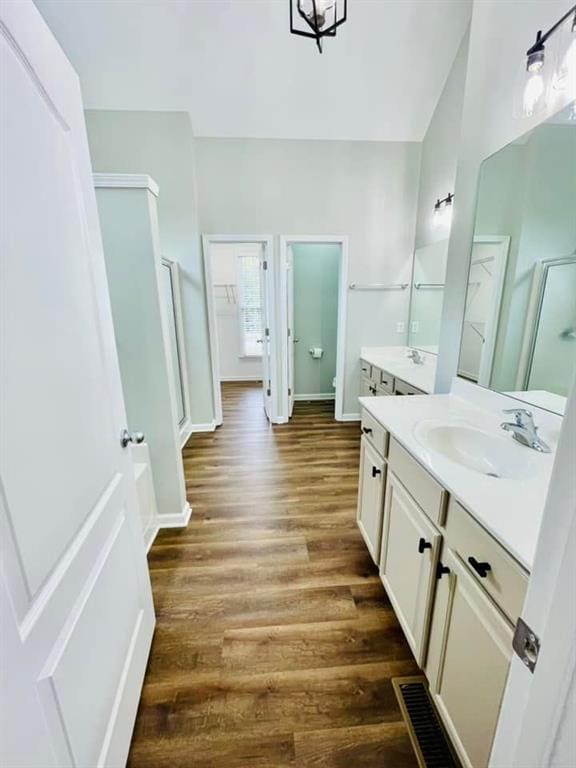 bathroom with toilet, a stall shower, vanity, wood finished floors, and baseboards