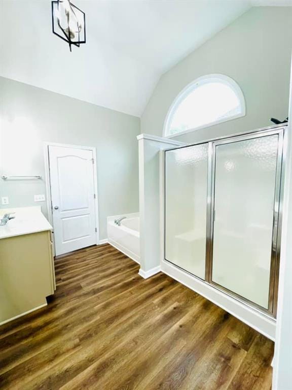 full bath with lofted ceiling, a shower stall, vanity, and wood finished floors