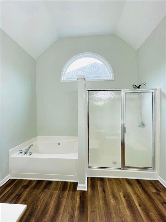 full bathroom featuring lofted ceiling, a garden tub, wood finished floors, baseboards, and a stall shower