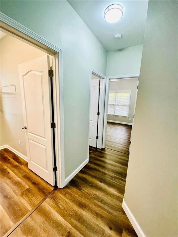 corridor with dark wood-style flooring and baseboards