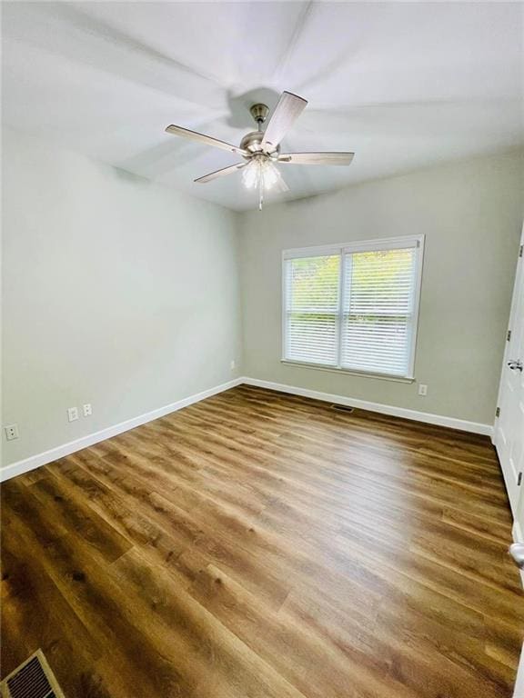 empty room featuring visible vents, dark wood-type flooring, a ceiling fan, and baseboards