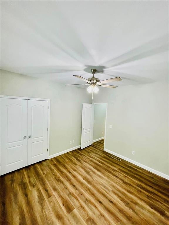 unfurnished bedroom featuring a ceiling fan, dark wood-style flooring, visible vents, and baseboards