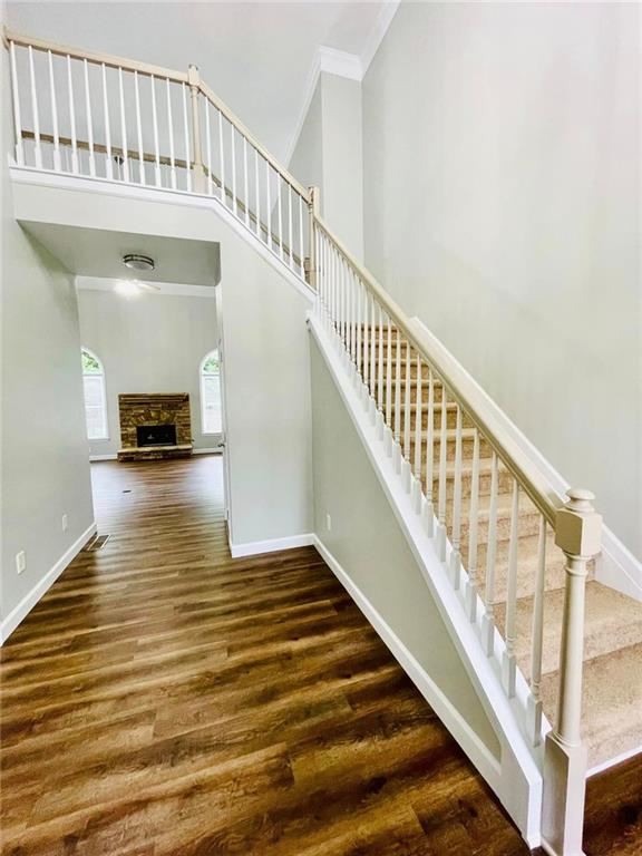 staircase with baseboards, a high ceiling, wood finished floors, and crown molding