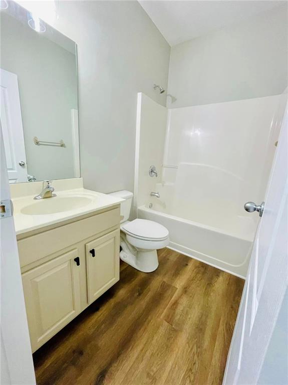 full bathroom with toilet,  shower combination, wood finished floors, and vanity