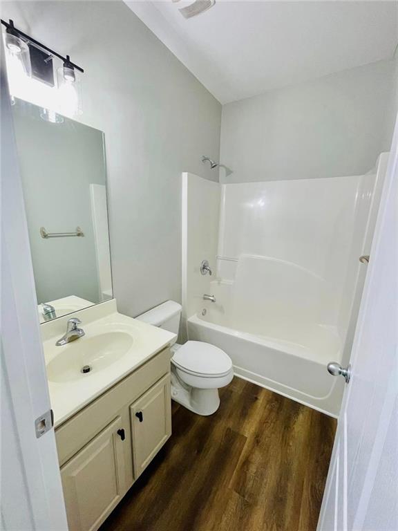 bathroom featuring toilet, bathtub / shower combination, wood finished floors, and vanity