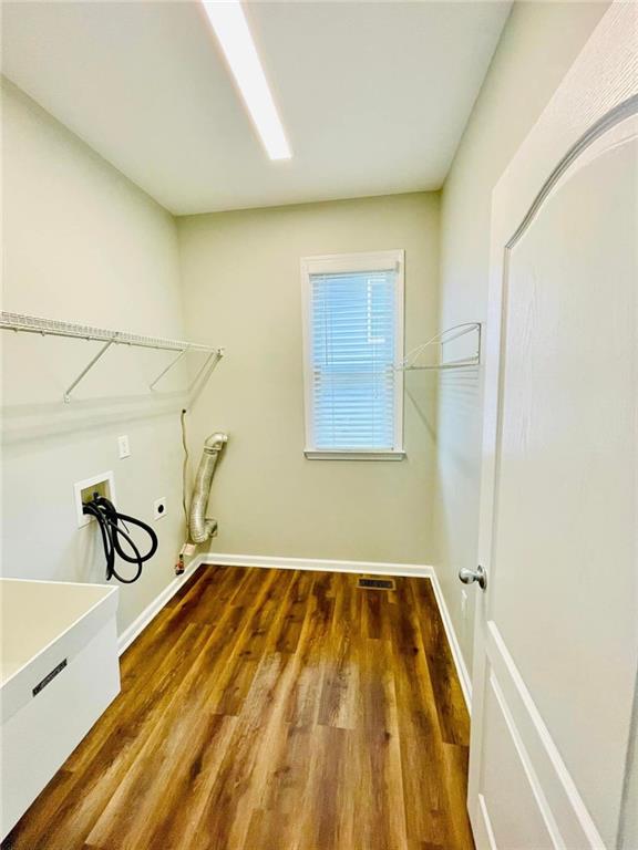 washroom with hookup for a washing machine, laundry area, dark wood finished floors, and baseboards