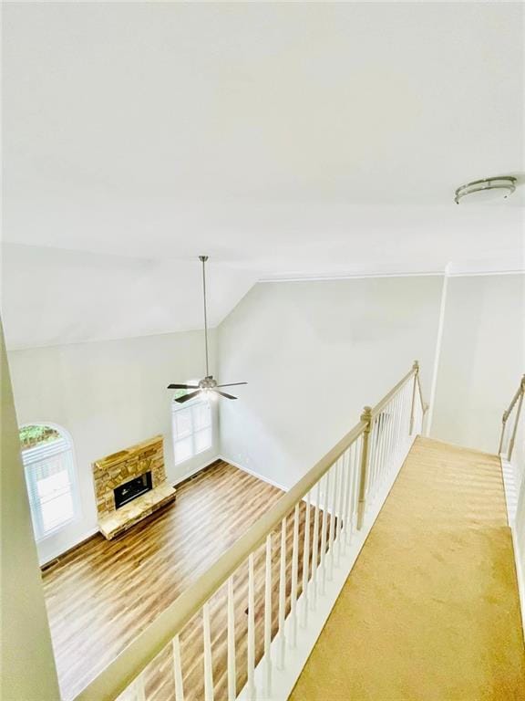 hallway with vaulted ceiling, an upstairs landing, and wood finished floors