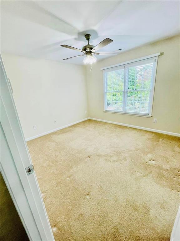 empty room featuring a ceiling fan, baseboards, and carpet flooring