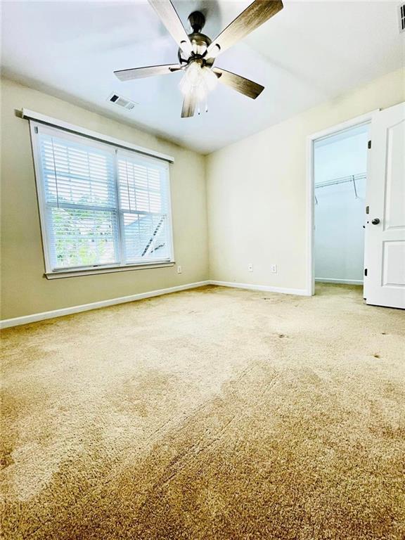 unfurnished room with a ceiling fan, baseboards, visible vents, and carpet flooring