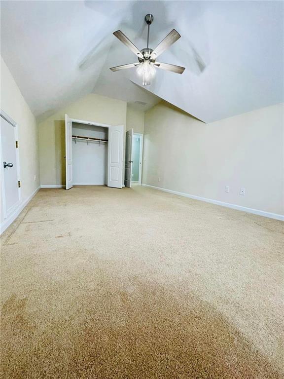 additional living space featuring vaulted ceiling, baseboards, a ceiling fan, and light colored carpet