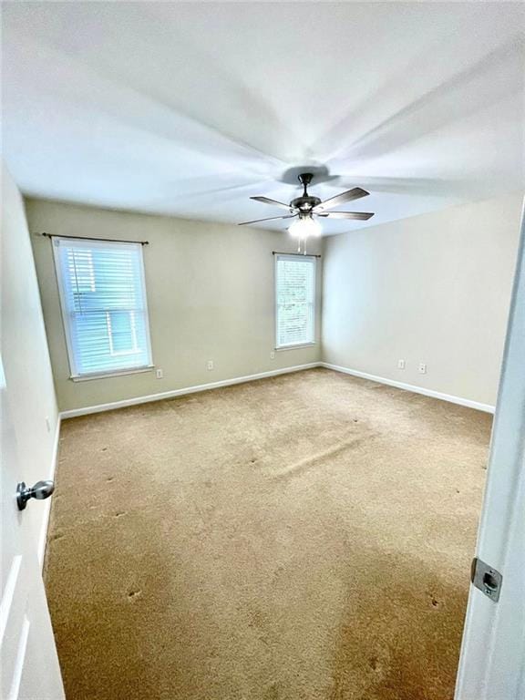 spare room featuring carpet floors, ceiling fan, and baseboards