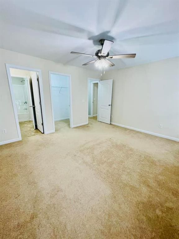 unfurnished bedroom with light carpet, baseboards, and ensuite bathroom