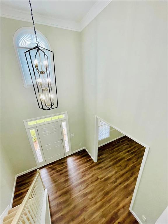 entrance foyer featuring an inviting chandelier, baseboards, ornamental molding, and dark wood-style flooring