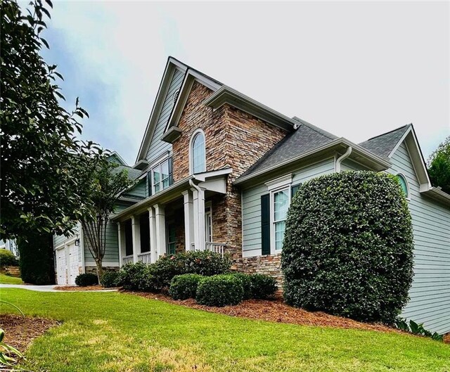 view of side of property featuring a garage, driveway, roof with shingles, and a yard