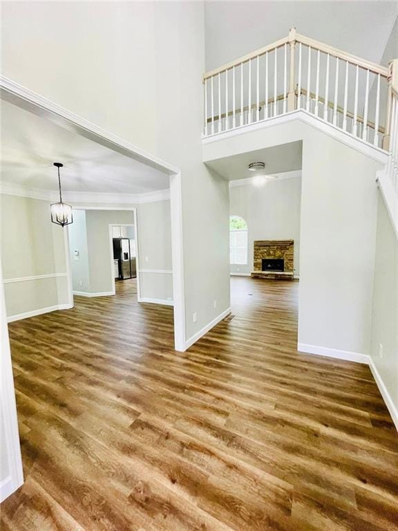 unfurnished living room with a stone fireplace, wood finished floors, and baseboards