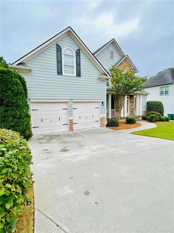 traditional-style home featuring an attached garage, stone siding, and driveway