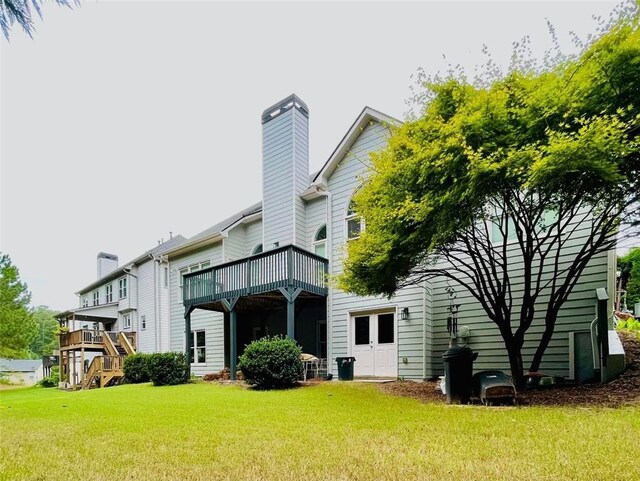 rear view of house featuring a yard, a chimney, and a wooden deck