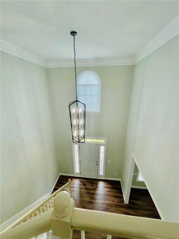 entrance foyer featuring baseboards, an inviting chandelier, wood finished floors, and crown molding