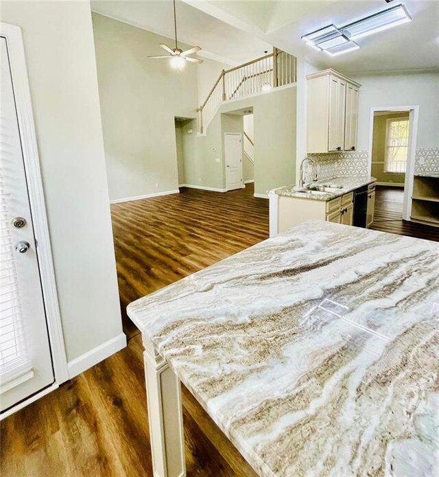 kitchen with dark wood finished floors, tasteful backsplash, open floor plan, white cabinets, and a sink