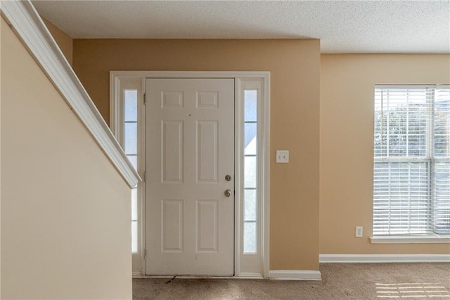 entrance foyer with light colored carpet and a textured ceiling