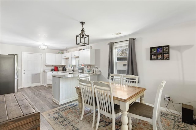 dining area with visible vents, baseboards, and wood finished floors