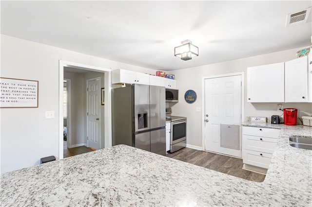 kitchen featuring visible vents, light stone counters, dark wood finished floors, white cabinetry, and appliances with stainless steel finishes