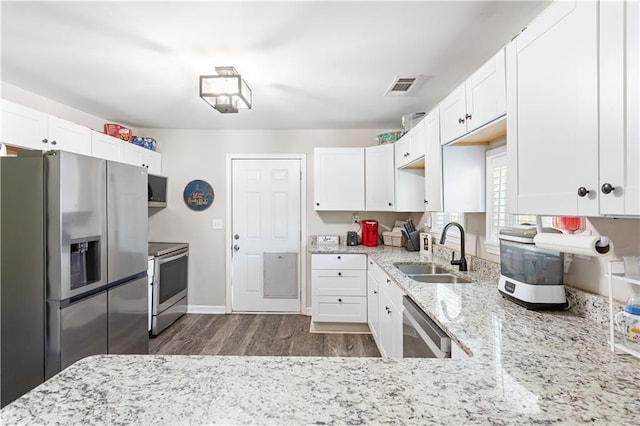 kitchen featuring white cabinets, light stone counters, appliances with stainless steel finishes, and a sink