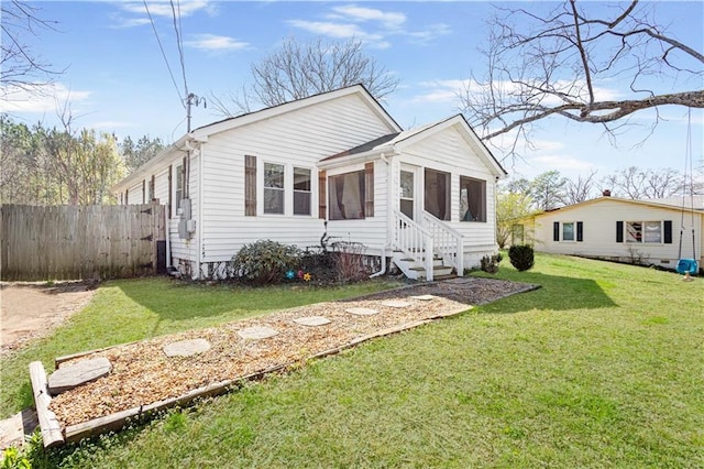 view of front facade with a sunroom, a front yard, and fence