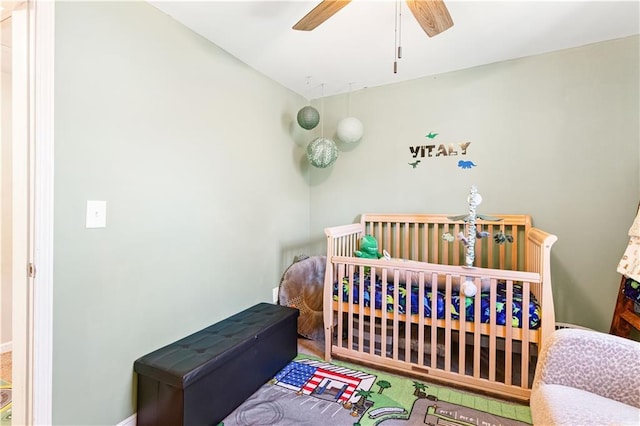 bedroom with a crib and a ceiling fan