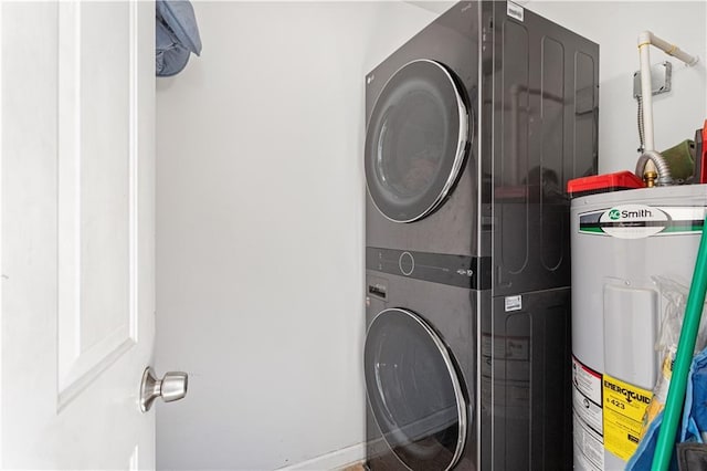 clothes washing area with water heater, laundry area, and stacked washer / dryer